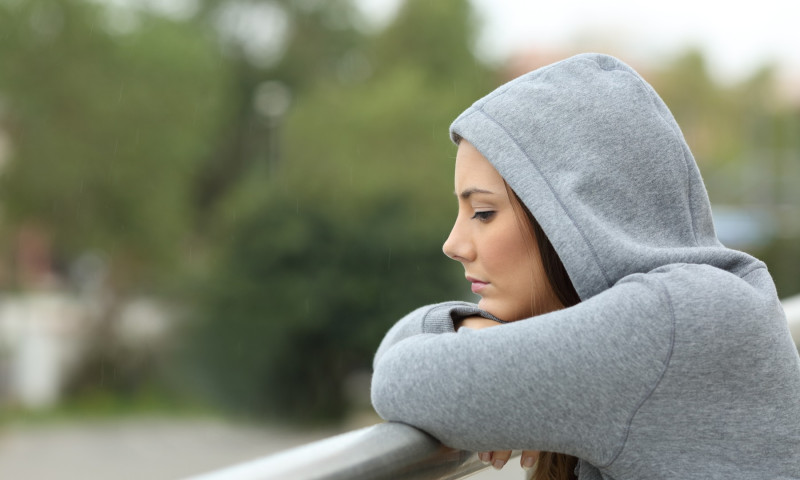 Sad teenager looking down in a balcony