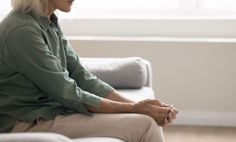 Weak vulnerable elderly woman sitting on sofa dealing with depression