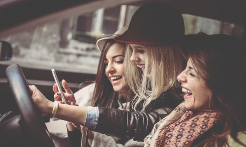 Three best friends in the car and reading  message on smart phone.