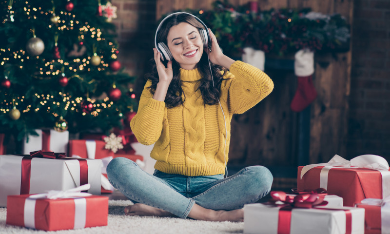 Full length body size photo of rejoicing nice overjoyed girl listening to christmas music rejoicing with new year atmosphere wearing yellow pullover jeans denim sitting on floor