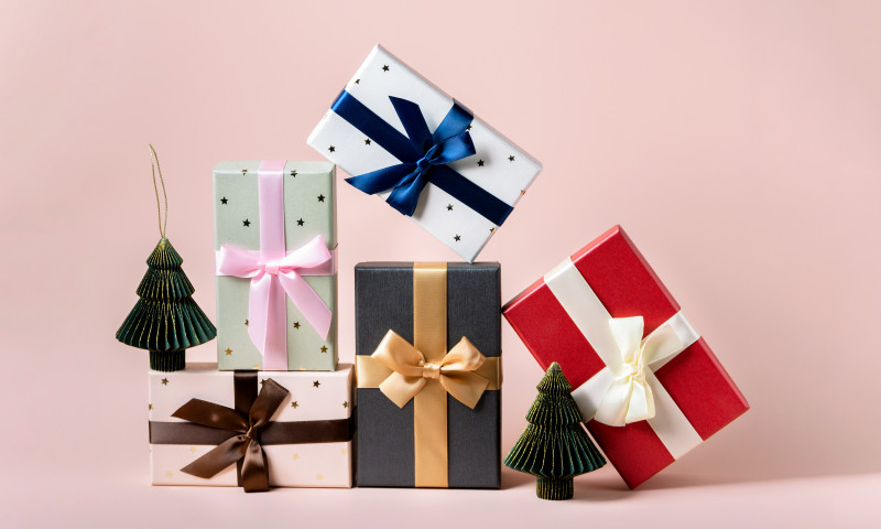 Festive christmas new year background colorful gift boxes and holiday decorations on pink background. New Year's present and Christmas present top view