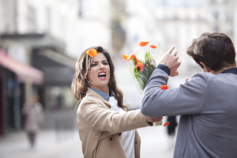 Woman hitting a man with a bouquet of flowers
