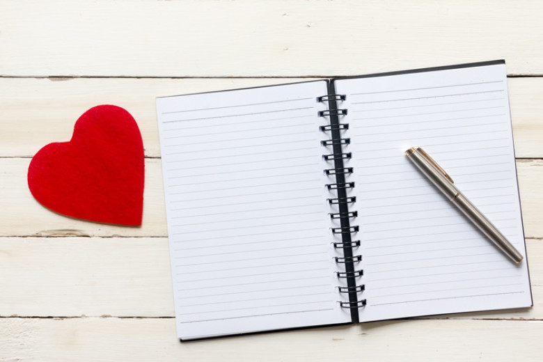 Open notebook with pen and heart shape.