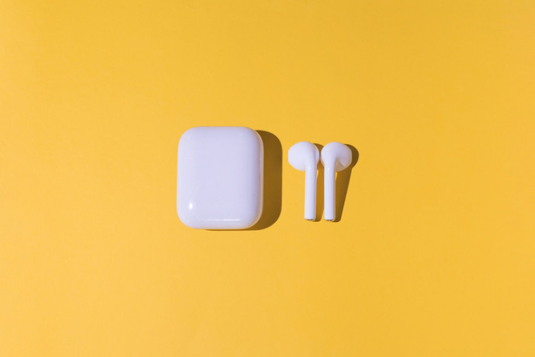 Trendy cordless white headphones on yellow background