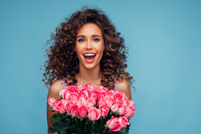 Happy young girl holding a big bouquet of pink roses