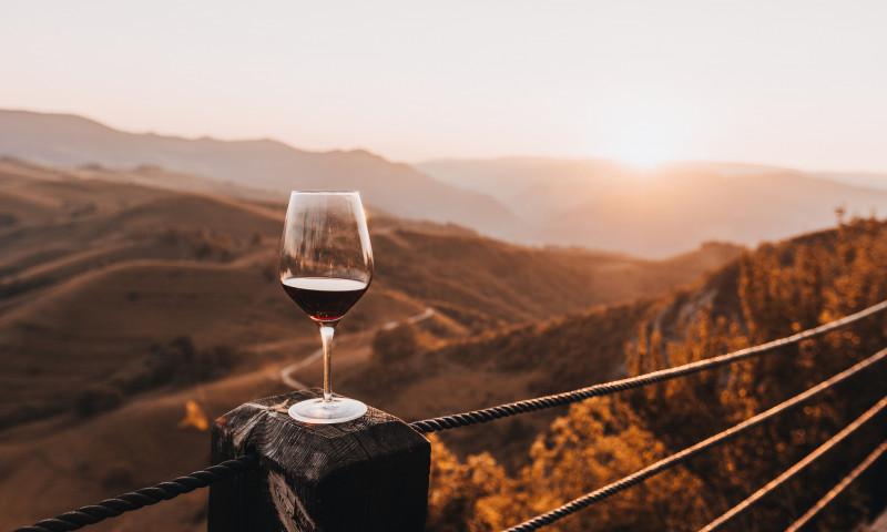 Glass of red wine at sunset against hills and mountains