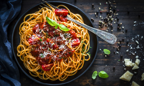 Spaghetti with tomato sauce shot on rustic wooden table