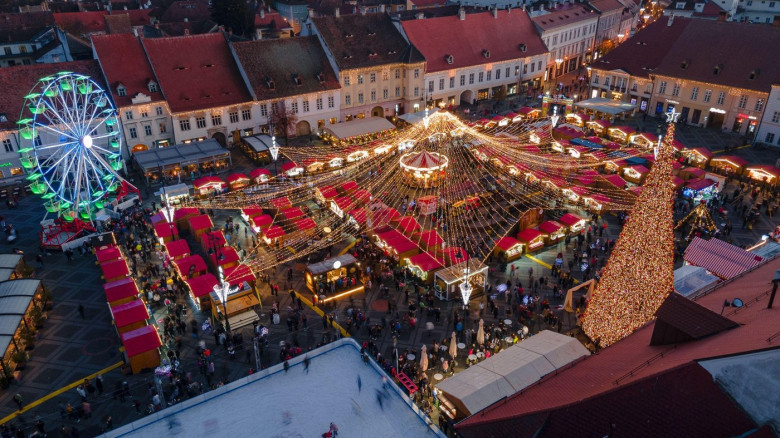 Landscape photography of Sibiu city center with the Christmas Fair, shot from a drone at sunset with the city lightning on. Birds eye view over citysc