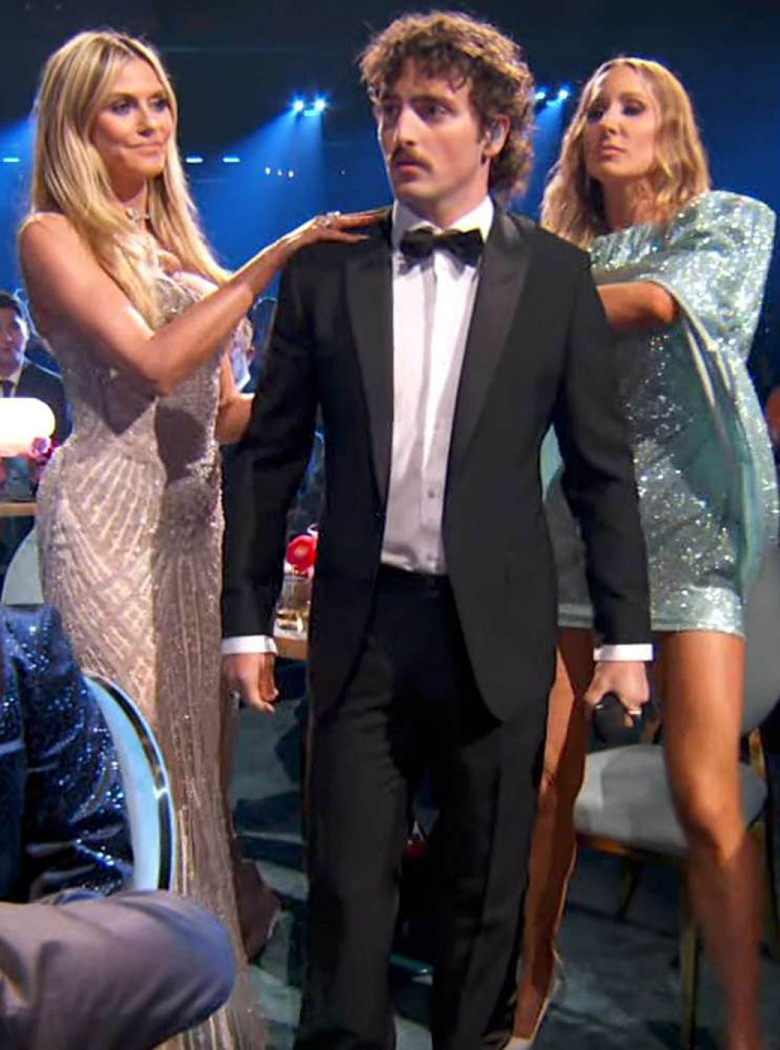 Benson Boone stripped from a suit into a sheer jumpsuit at the 2025 Grammys with help from Heidi Klum and Nikki Glaser.