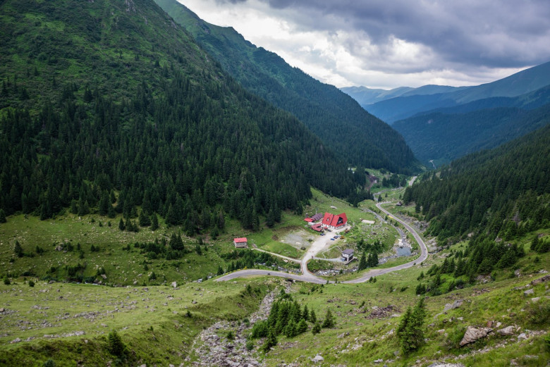 Transfagarasan Road (DN7C) crossing the southern section of the Carpathian Mountains in Romania. Aerial view with a small hotel in a valley