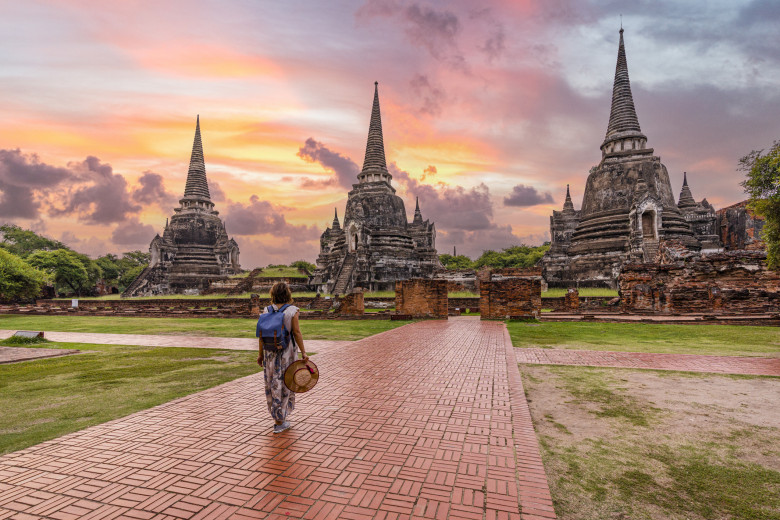 Woman walking to Wat Phra Si Sanphet temple at dawn, Thailand