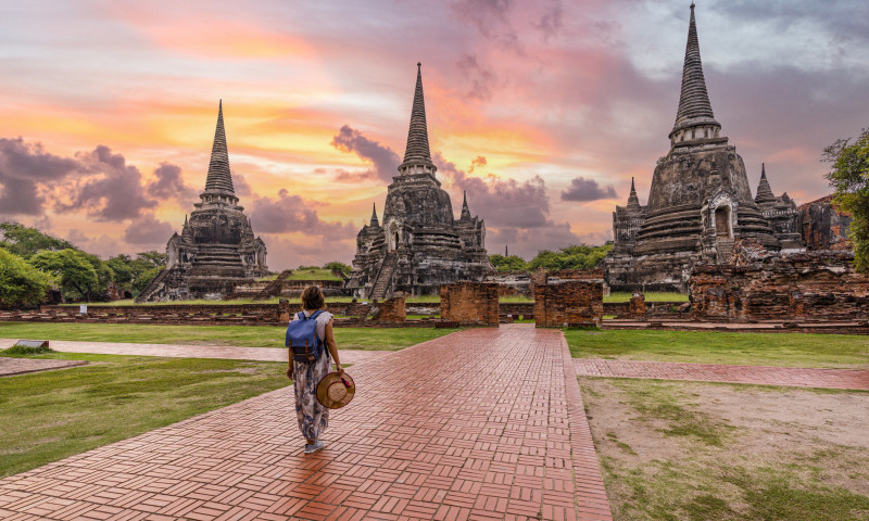 Woman walking to Wat Phra Si Sanphet temple at dawn, Thailand