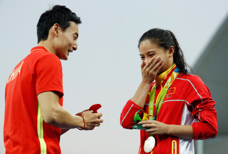 RIO DE JANEIRO, BRAZIL - AUGUST 14: Chinese diver Qin Kai proposes to silver medalist He Zi of China on the podium during the medal ceremony for the Women's Diving 3m Springboard Final on Day 9 of the Rio 2016 Olympic Games at Maria Lenk Aquatics Centre on August 14, 2016 in Rio de Janeiro, Brazil. (Photo by Clive Rose/Getty Images)