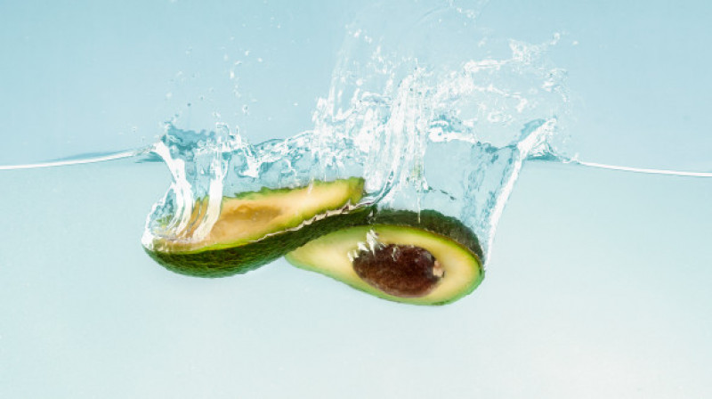 Ripe,Avocado,Halves,Sinking,Into,Clear,Water,,Blue,Background