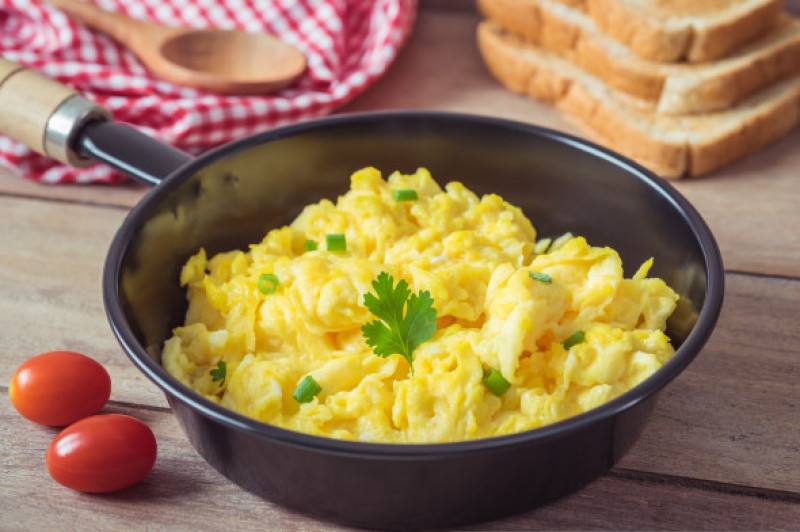 Scrambled,Eggs,In,Frying,Pan,And,Toast,On,Wooden,Table