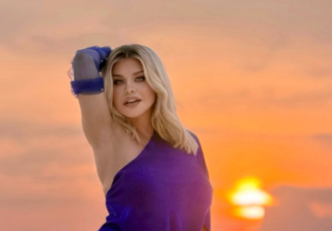 Loredana Groza, pe o plajă din Maldive, la apus, îmbrăcată într-o rochie cu crăpătură până la șold. Exprimă senzualitate și încredere fără limite