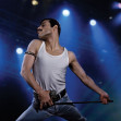 rami malek in rolul lui freddie mercury tine microfonul in mana si imita una din miscarile solistului queen