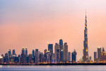 Stunning panoramic view of the illuminated Dubai skyline during sunset with beautiful shades of pink and orange colors.