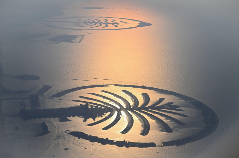 Dubai, United Arab Emirates. 01st Dec, 2023. View of the artificial archipelago of The Palm Jumeirah in the Persian Gulf from a height of around 2000 meters. The backlight of the low evening sun colors the water reddish to orange. About five kilometers aw