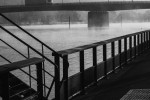 The River Seine at Vernon, Normandy, France. | Monochrome image of a misty river with a bridge in the background, viewed from behind a metal railing.