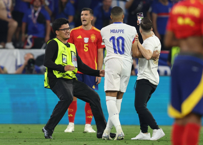 Munich, Germany, 9th July 2024. A pitch invader takes a selfie with Kylan Mbappe of France during the UEFA European Cham