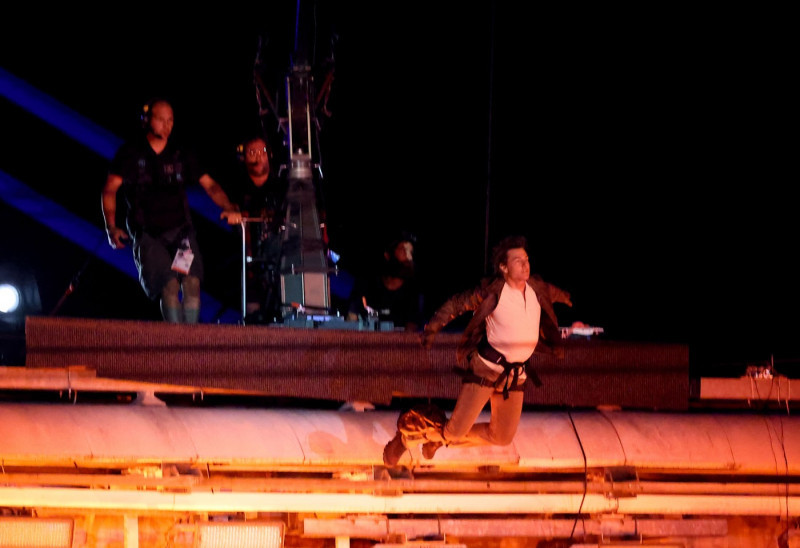 Tom Cruise, accroché à un fil, descend du toit du stade de France pour prendre le drapeau olympique