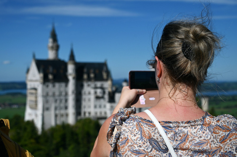 Touristin fotografiert Schloss Neuschwanstein im bayerischen Allgäu bei Füssen, Deutschland *** Tourist takes photo of N