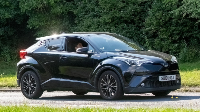 Milton Keynes,UK - July 18th 2024: 2018 black Toyota C-HR hybrid electric car driving on a British country road