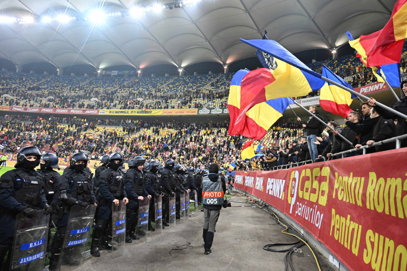 Suporterii romani flutura steagurile tricolore alaturi de un cordon de jandarmi dupa meciul de fotbal dintre Romania si