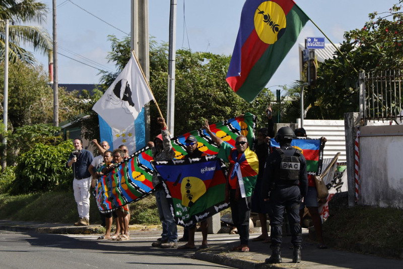 People demonstrate as French President Emmanuel Macron's motorcade drives past in Noumea, France's Pacific territory of New Caledonia on May 23, 2024. Macron flew to France's Pacific territory of New Caledonia on a politically risky visit aiming to defuse