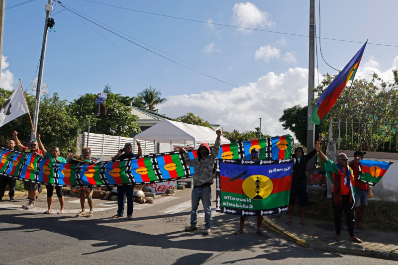 People demonstrate as French President Emmanuel Macron's motorcade drives past in Noumea, France's Pacific territory of New Caledonia on May 23, 2024. Macron flew to France's Pacific territory of New Caledonia on a politically risky visit aiming to defuse