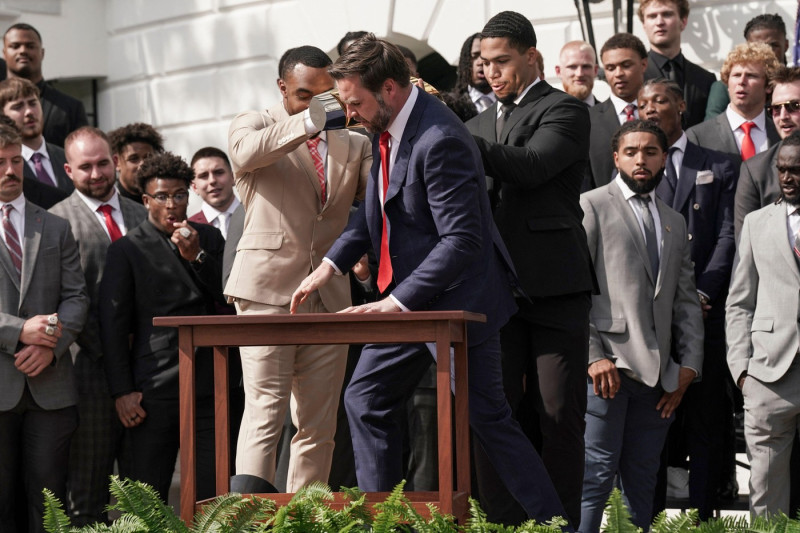 Ohio State University football player TreVeyon Henderson, left, catches the top of the team's championship trophy after Vice President JD Vance tries to pick it up when President Trump welcomed the 2025 College Football National Champions - The Ohio State