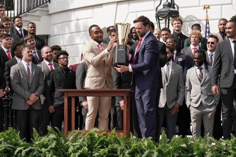 Ohio State University football player TreVeyon Henderson, left, catches the top of the team's championship trophy after Vice President JD Vance tries to pick it up when President Trump welcomed the 2025 College Football National Champions - The Ohio State