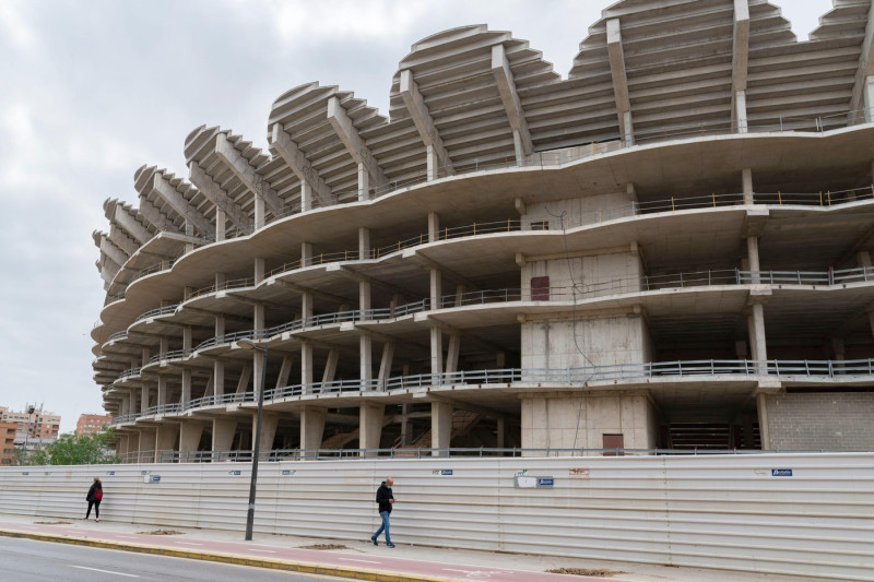 A man wearing a face mask walks past the works of the Nou Mestalla stadium.In August 2007 work began on the construction of the Nou Mestalla football stadium, but in February 2009 construction was halted due to the poor economy of Valencia CF. Twelve year