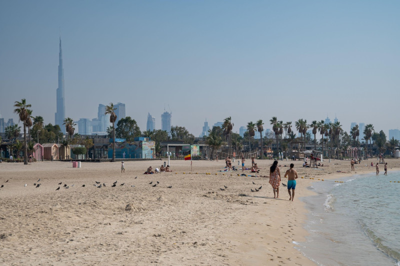 17.03.2025, Dubai, United Arab Emirates, Asia - People enjoy a sunny day on Jumeirah Beach with the Burj Khalifa skyscraper and the city skyline.