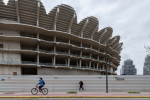 A woman wearing a face mask walks past the works of the Nou Mestalla stadium.In August 2007 work began on the construction of the Nou Mestalla football stadium, but in February 2009 construction was halted due to the poor economy of Valencia CF. Twelve ye