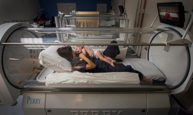 Jesse Arrigo and his mother, Kristin, lie in a hyperbaric chamber