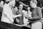 File photo dated 30/07/1966 of England captain Bobby Moore holds the Jules Rimet Trophy, collected from the Queen Elizabeth II, after leading his team to a 4-2 victory over West Germany, in an exciting World Cup Final that went to extra time at Wembley, L