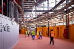 30 March 2022, Qatar, Doha: Workers walk through an aisle at Stadium 974 during a Fifa media tour. 974 brightly arranged shipping containers were used to build the stadium. Doha will host the Fifa Congress on March 31 and the draw for the 2022 World Cup i