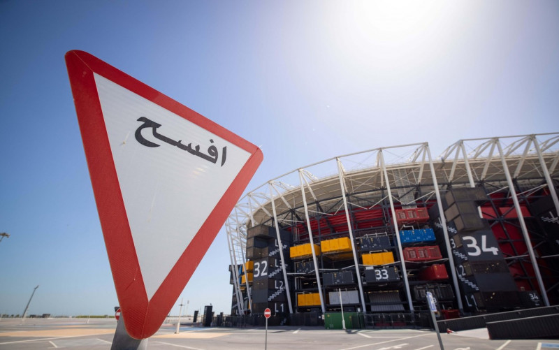 Doha, Qatar. 30th Mar, 2022. A traffic sign in Arabic stands next to Stadium 974 during a Fifa media tour. For the construction of the stadium 974 colorfully arranged shipping containers were used. Doha will host the Fifa Congress on March 31 and the draw