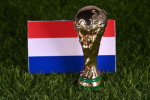 November 13, 2022, Doha, Qatar. FIFA World Cup trophy on the background of the flag of the Netherlands on the green lawn of the stadium.