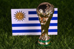 November 13, 2022, Doha, Qatar. FIFA World Cup trophy on the background of the flag of Uruguay on the green lawn of the stadium.