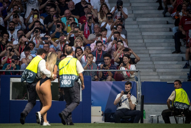 Supporters and staff take photos as streaker Kinsey Wolanski is escorted off the pitch during the UEFA Champions League FINAL match between Tottenham Hotspur and Liverpool at the Metropolitano Stadium (Stadium Metropolitano), Av. de Luis Aragons, 4, 2802