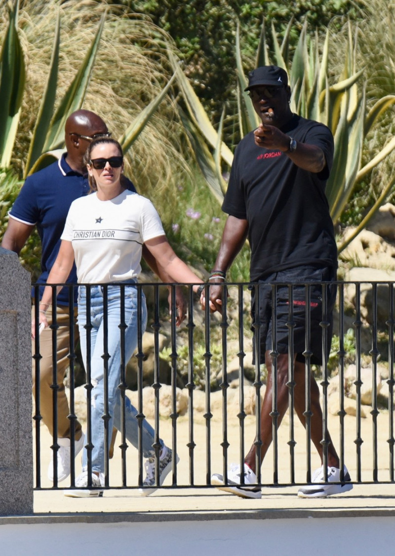EXCLUSIVE: Basketball legend Michael Jordan is seen smoking a cigar while out for a walk his wife, Yvette Prieto in Marbella