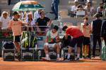 Spain s Carlos Alcaraz makes a break and touches his leg after he hurt himself during the men s singles match against Se