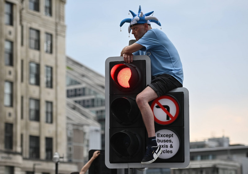 Manchester, England, 12th June 2023. A Manchester City fan climbs up for a better vantage point on a traffic light durin