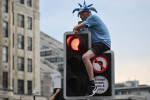 Manchester, England, 12th June 2023. A Manchester City fan climbs up for a better vantage point on a traffic light durin