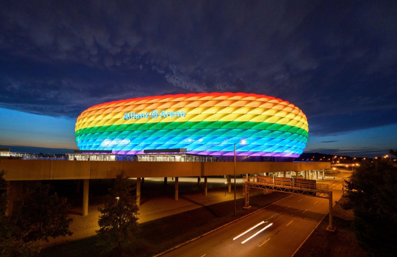 People on the Frttmaninger Mllberg on the occasion of Christopher Street Day in Munich, the Allianz Arena is illuminated in rainbow colors, which symbolize the colors of the LBGTQ movement in Munich. Bavaria, Germany, July 10, 2021. LGBTQ stands for lesb