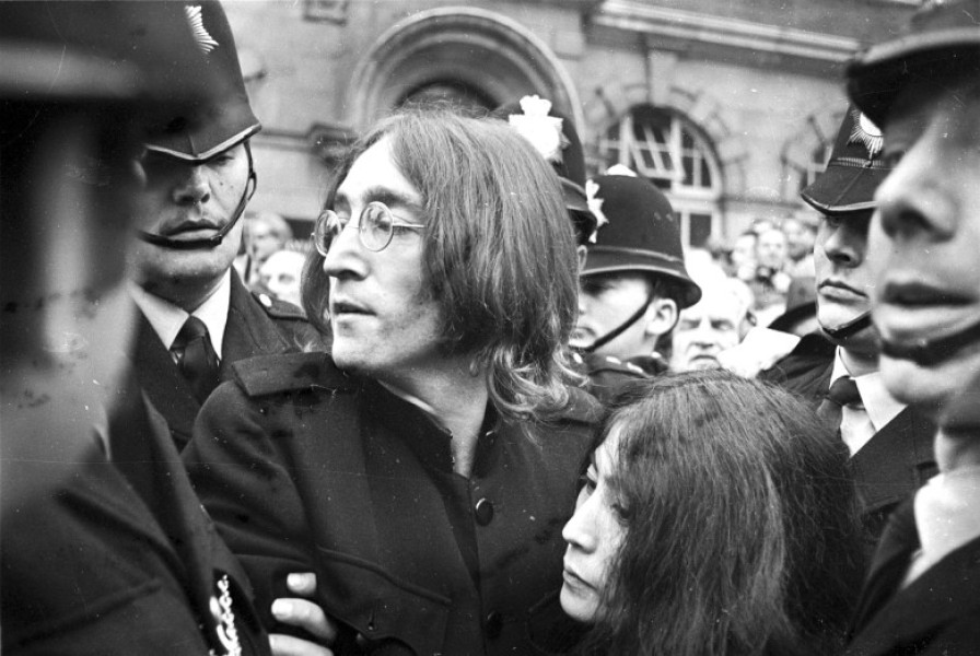 John Lennon protects Yoko Ono after crowds tried to mob them after they left a London Court Hearing Charges of Possession of Marijuana and Obstructing Police. The pair were released on bail of Ł100 until their trial on 28th November.London - 19th October
