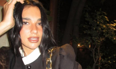 Dua Lipa, doar în body strâns pe corp, roșu strălucitor, și mănuși asortate. Combinația perfectă de supereroină și artistă de cabaret